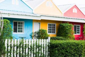 une maison colorée avec une clôture blanche devant elle dans l'établissement Jasmine Resort, à Buriram