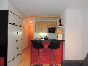 a kitchen with a red island and black stools at Lona C 43 in Grimentz