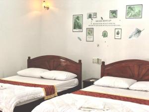 two beds in a room with pictures on the wall at Anh Xuan Guest House in Hue