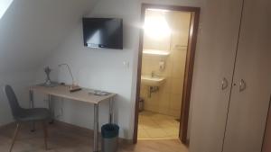 Habitación con escritorio y baño con TV en la pared. en Hotel & Hostel Marenberg Radlje, en Radlje ob Dravi