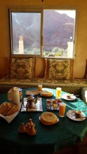 einen Tisch mit Speisen und Getränken auf einem Tisch mit Fenster in der Unterkunft Auberge Restaurant Zahra in Boumalne