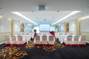 a banquet hall with white tables and chairs and a screen at The Empress Premier Chiang Mai - SHA Extra Plus in Chiang Mai