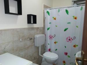 baño con aseo y cortina de ducha con flores en Casa Charlotte 1 & Casa Charlotte 2, en Mongiove