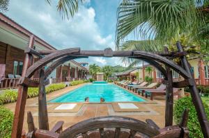 una piscina en un complejo con un arco de madera en Khum Laanta Resort - SHA Extra Plus, en Ko Lanta