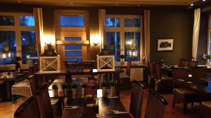 a dining room with tables and chairs and windows at Hotel Knipper in Lastrup
