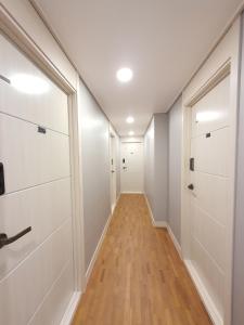 a hallway with white walls and wood floors and a door at Dawoo House 2 in Hongdae in Seoul