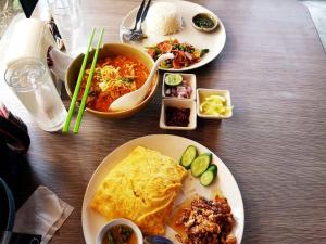 a wooden table with plates of food on it at VK &Residence in Kanchanaburi City