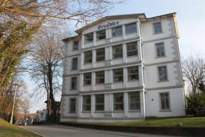 ein weißes Gebäude am Straßenrand in der Unterkunft Adlerhorst im Haus Seeadler in Zinnowitz