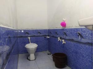 La salle de bains est pourvue de carrelage bleu, de toilettes et d'un lavabo. dans l'établissement Madhav Farmhouse, à Sasan Gir