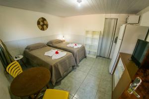 a room with two beds and a table and a refrigerator at Suíte Abreu Noronha in Fernando de Noronha