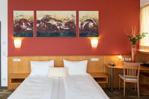 a bedroom with a bed and a desk and paintings at Hotel Bokan Exclusiv in Graz