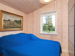 a bedroom with a blue bed and a window at Holiday home Væggerløse LXII in Marielyst