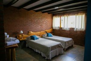 1 dormitorio con 2 camas y pared de ladrillo en Hostería La Portada en Trevelín
