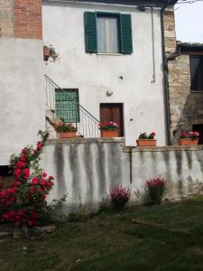 une maison blanche avec des volets verts et des fleurs dans l'établissement Magrignano tra animali e natura, à Montieri