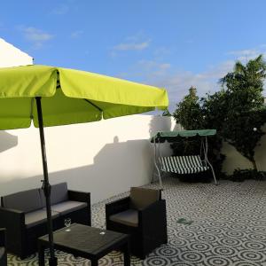 een patio met een groene parasol, stoelen en tafels bij Helena's House in Ponta Delgada