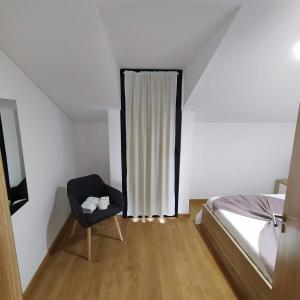 um quarto com uma cama e uma cadeira ao lado de uma janela em Helena's House em Ponta Delgada