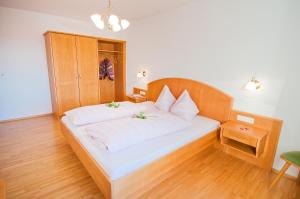 a bedroom with a large white bed with a wooden headboard at Berggasthof Bliembauer in Altenmarkt im Pongau