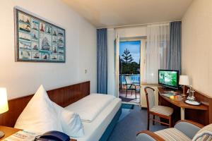 ein Hotelzimmer mit einem Bett und einem Schreibtisch mit einem Computer in der Unterkunft Hotel Seeschwalbe in Cuxhaven