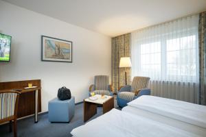 ein Hotelzimmer mit einem Bett und zwei Stühlen in der Unterkunft Hotel Seeschwalbe in Cuxhaven + 37 Fotos