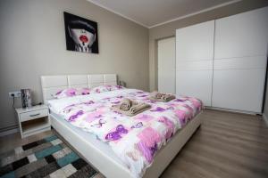 een slaapkamer met een bed met een roze en wit dekbed bij Travel Homzzz Central Apartments - Tusnad in Târgu-Mureş