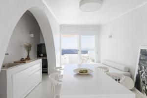 uma cozinha branca com uma mesa e cadeiras brancas em Aesthesis Boutique Villas Fira em Fira