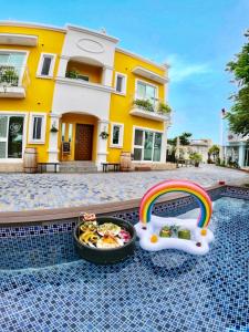 a pool with a bowl of food and a rainbow next to a house at Burano Yellow Villa in Hengchun