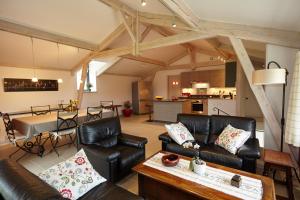 ein Wohnzimmer mit schwarzen Ledermöbeln und eine Küche in der Unterkunft La Tour de Ginaillac Gîte JACQUES BREL 5 étoiles in Les Arques