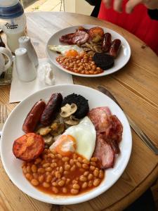 two plates of breakfast food on a wooden table at Haybow Farm Accommodation in Weston-super-Mare