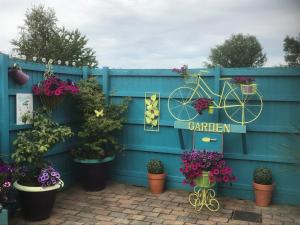 a blue fence with plants and a bicycle sign on it at Haybow Farm Accommodation in Weston-super-Mare