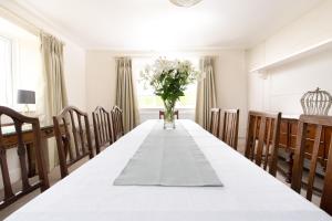 a dining room with a long table with a vase of flowers at Braunton Farmhouse in Braunton