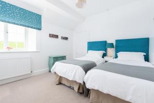 two beds in a white room with blue accents at Braunton Farmhouse in Braunton