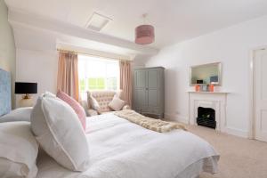 a bedroom with a large white bed and a fireplace at Braunton Farmhouse in Braunton