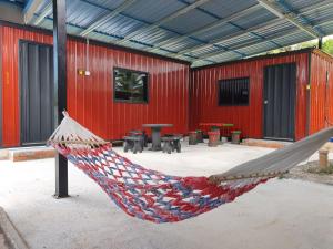 a hammock in front of a red building at Padang Besar Red Cabin Homestay in Padang Besar