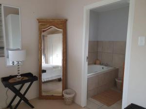 a bathroom with a tub and a mirror and a bed at WOODPECKER in Plettenberg Bay