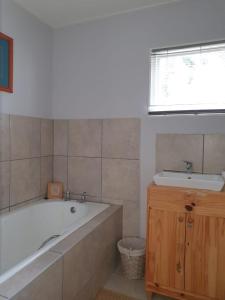 a bathroom with a bath tub and a sink at WOODPECKER in Plettenberg Bay