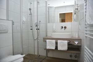 a bathroom with a shower and a sink and a mirror at Hotel-Skischule Krallinger in Obertauern