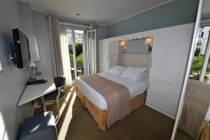a bedroom with a bed and a desk and a television at Hôtel de Provence in Cannes