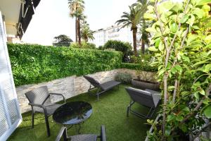 a patio with chairs and tables and a hedge at Hôtel de Provence in Cannes