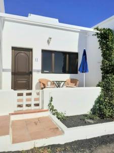 Biały dom z dwoma krzesłami i parasolem w obiekcie Los Ancones Apartment w Costa Teguise