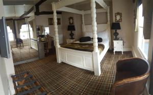 a bedroom with a canopy bed and a chair at The White Hart in Great Yeldham
