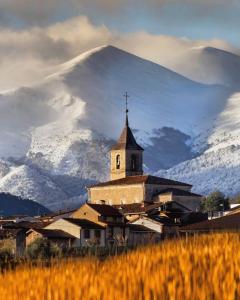 una iglesia con una montaña cubierta de nieve en el fondo en Casa Rural Nestazar II en Berceo