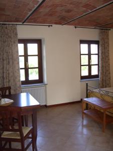 Habitación con mesa, sillas y ventanas. en B&B Cascina Gaione Via Gallina,18b 12052 Neive cn, en Neive