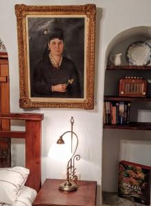 a framed portrait of a woman on a wall with a lamp at Kanto's Guesthouse in Stemnitsa