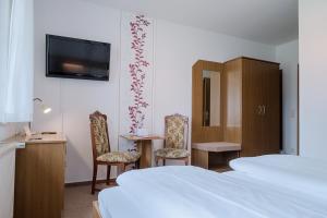 um quarto de hotel com duas camas e uma mesa e cadeiras em Hotel & Restaurant Lindengarten em Lübben