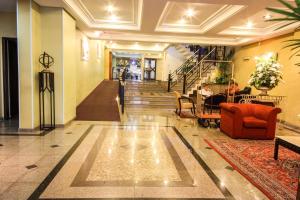 vestíbulo con sofá rojo, sillas y escaleras en Trevi Hotel e Business, en Curitiba