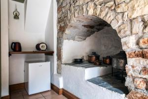 una habitación con horno de piedra y nevera blanca. en Kanto's Guesthouse, en Stemnitsa