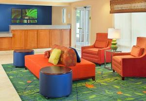 sala de estar con sofá naranja y 2 sillas en Country Inn & Suites by Radisson, Fayetteville I-95, NC, en Fayetteville