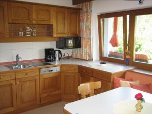 a kitchen with wooden cabinets and a table and a window at Ferienwohnungen Pötscher Maria in Matrei in Osttirol