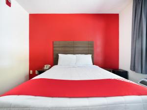 OYO Hotel Decatur I-285 The Perimeter في ديكاتور: غرفة حمراء مع سرير بجدار احمر