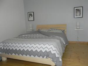 1 dormitorio con 1 cama con edredón gris y blanco en Nid de cigognes, en Rosheim